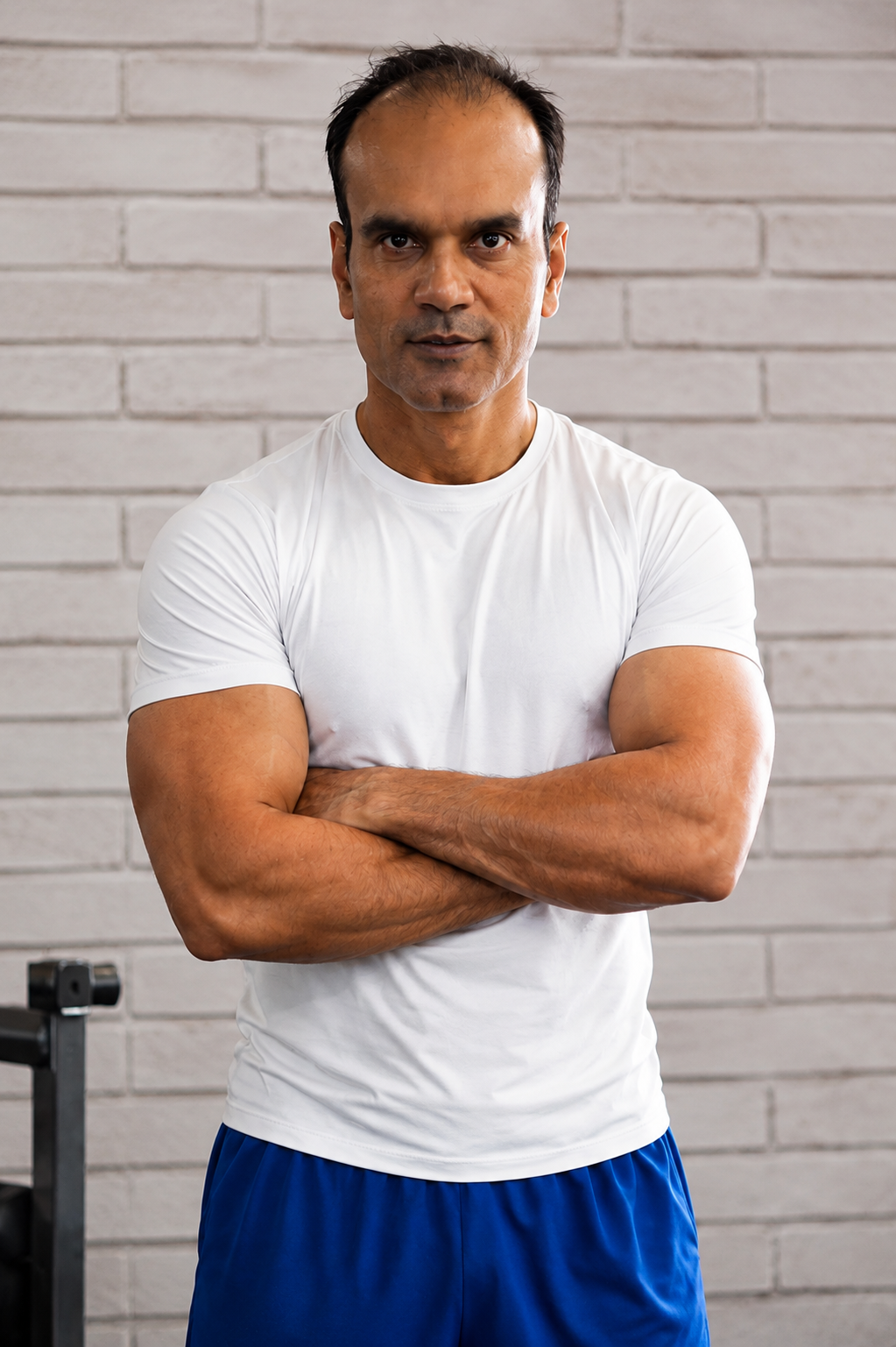 Santosh Kumar standing against a white brick wall